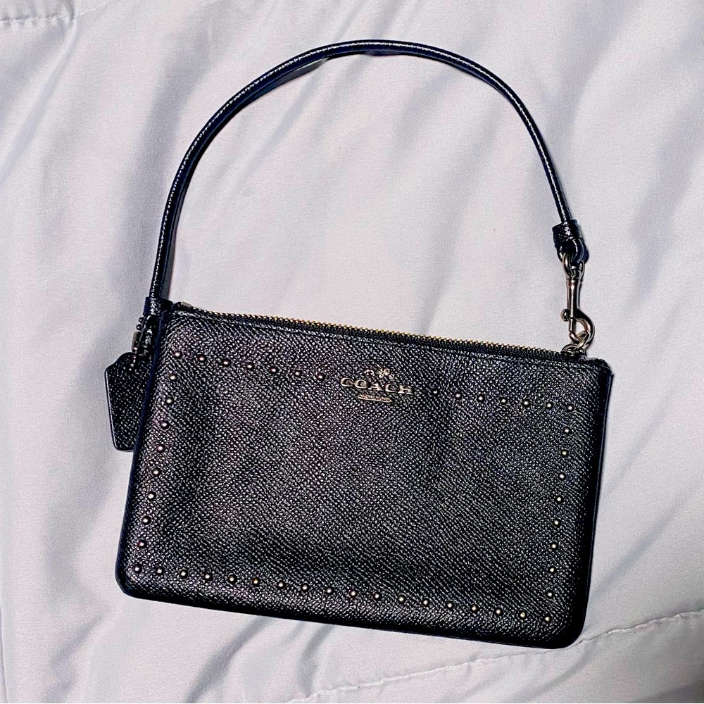 Black coach wristlet pebbled leather black/chrome studs and metal lettering.